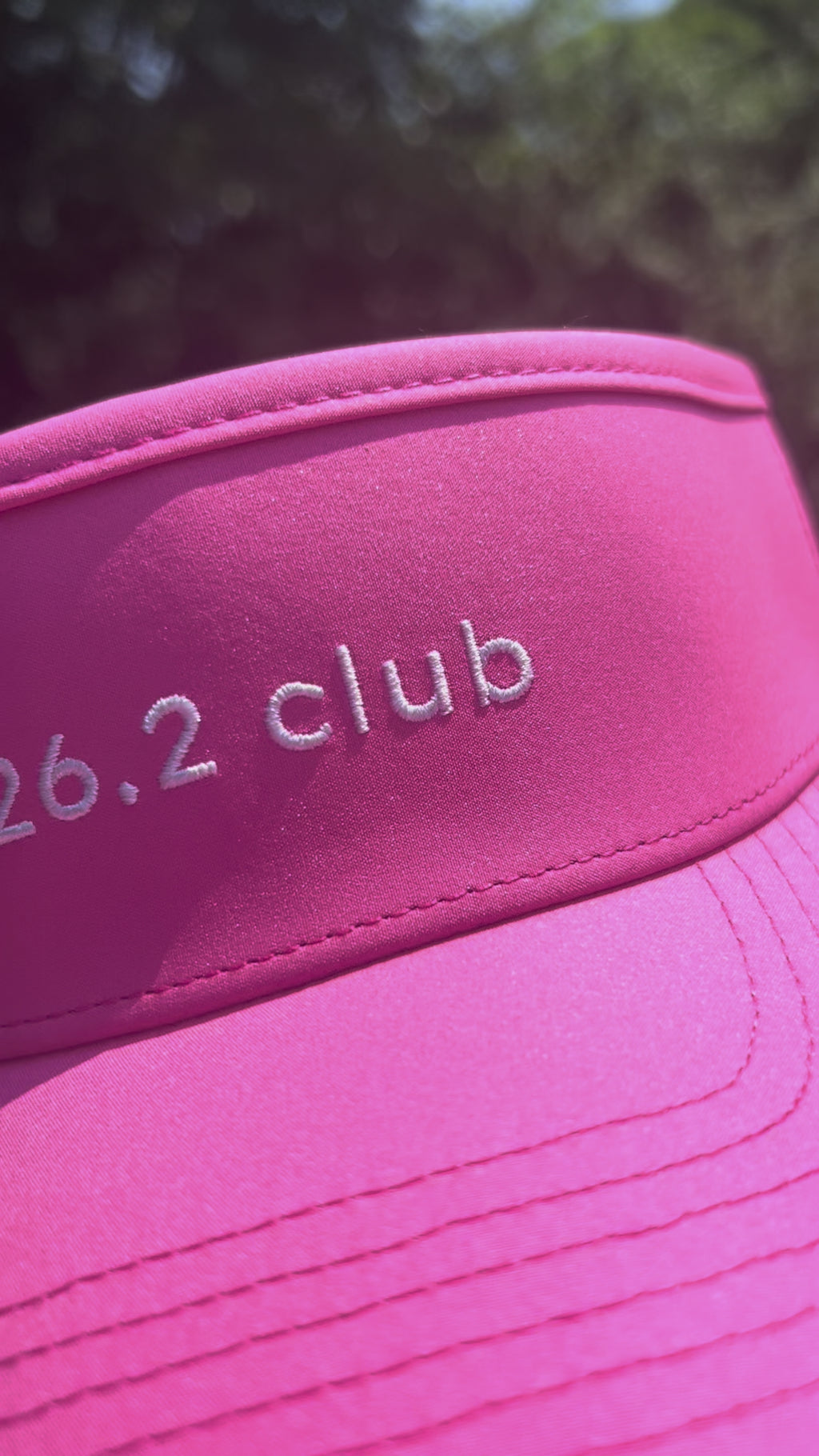 Girl wearing '26.2 club' pink visor outside and showing close-ups